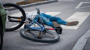 A man on laying on the road with a fallen bike right next to him.