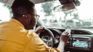An Uber driver scrolling through his phone while driving.