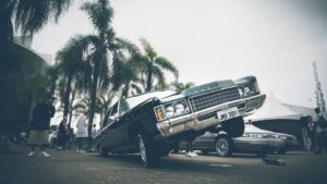 A green lowrider with hydraulics jumping on one side.