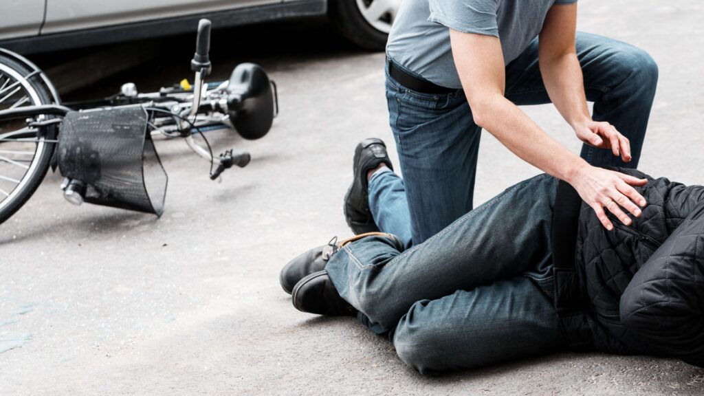 A person making sure a an injured bicyclist is alright.