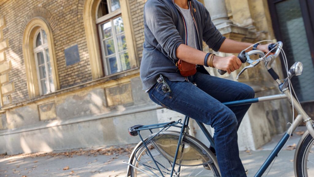 A person riding a bike on the sidewalk in a city.