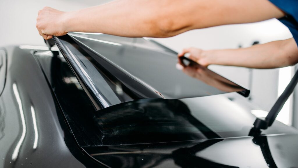 A person installing tint onto a car's back window.