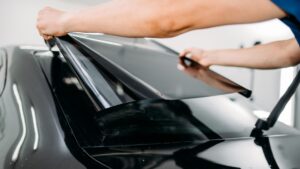 A person installing tint onto a car's back window.