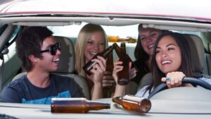 Three women and a man drinking alcohol in a car.