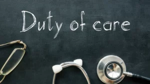 A chalk board with the phrase "Duty of Care" written with a pair of glasses and a stethoscope.