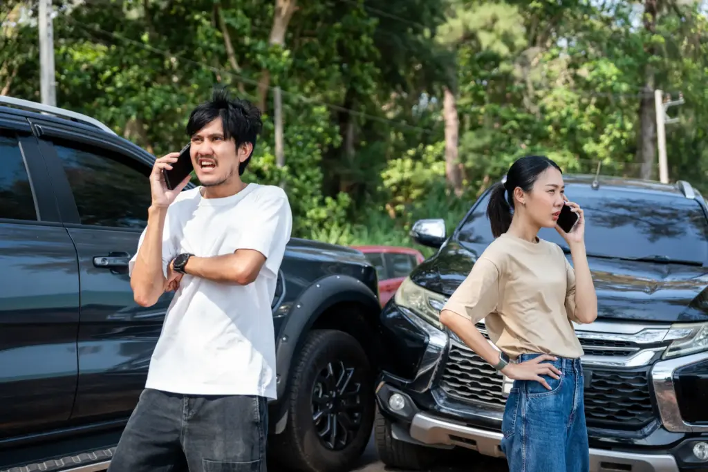 Two people on their phones after a car accident.