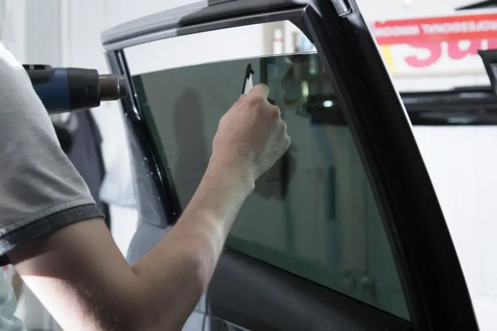 A person putting on a window tint on a car window.