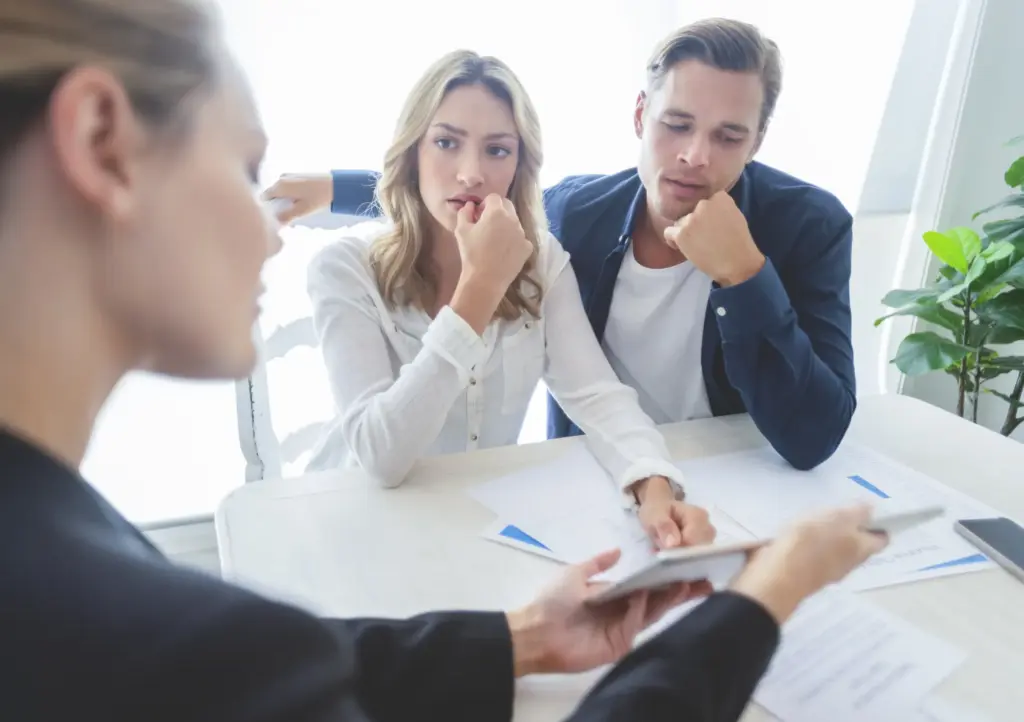 A pair of confused clients looking at a woman explaining some documents to them.