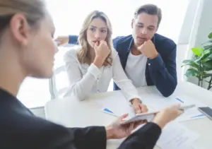 A pair of confused clients looking at a woman explaining some documents to them.