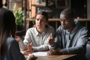 A stressed couple arguing something to a person.